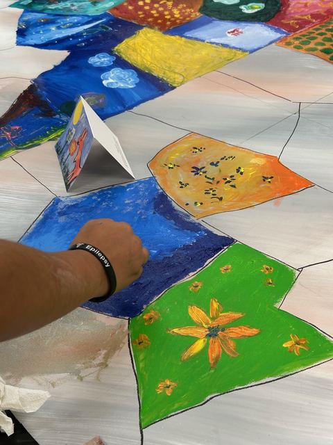 Close-up of hands painting flowers on a section of the group mural