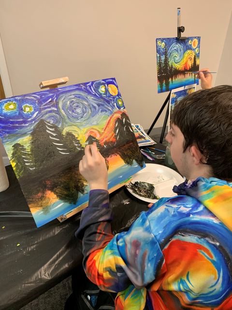 A Joyful Arts artist painting a starry night sky on canvas at an easel