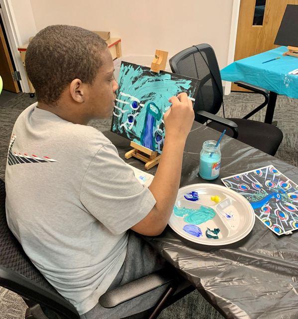 A young artist painting an abstract blue canvas during a Saturday class