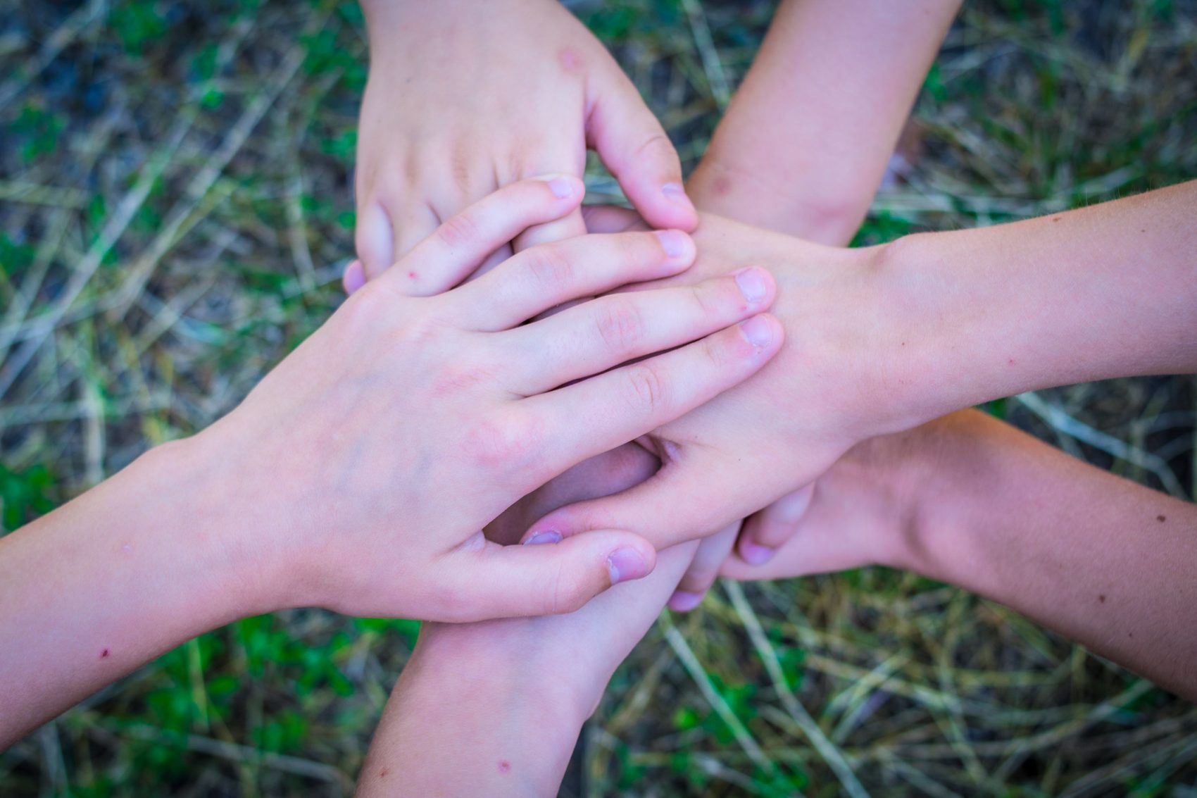 Las manos de varias personas apiladas en un círculo, simbolizando unidad y trabajo en equipo.